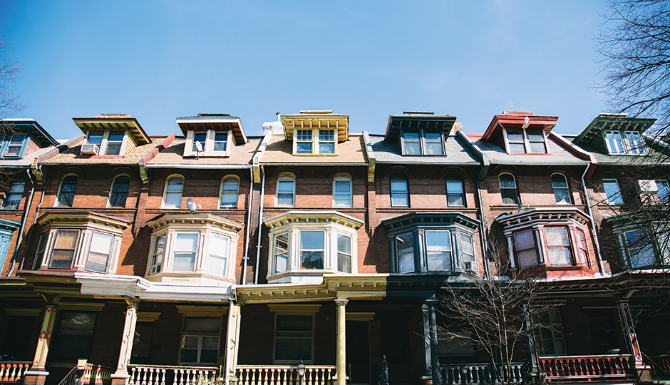A row of classic Philadelphia brick rowhomes against a clear blue sky
